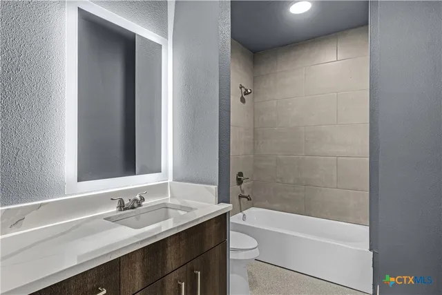 a bathroom with a granite countertop sink a toilet and bathtub