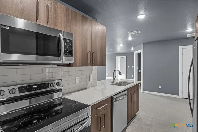 a kitchen that has a sink and a stove top oven