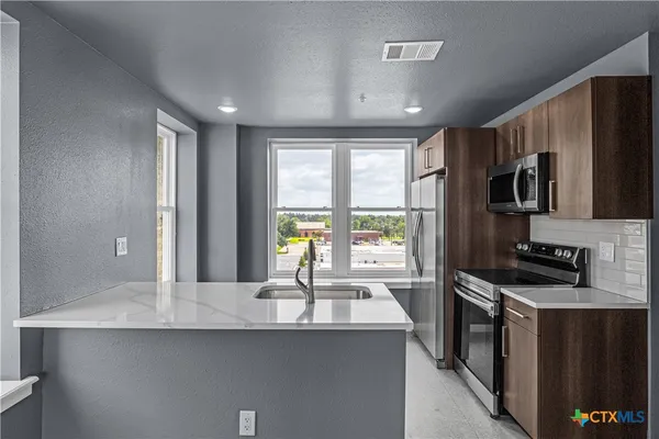 a kitchen with stainless steel appliances a sink stove and refrigerator