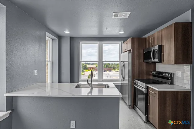 a kitchen with stainless steel appliances a sink stove and refrigerator