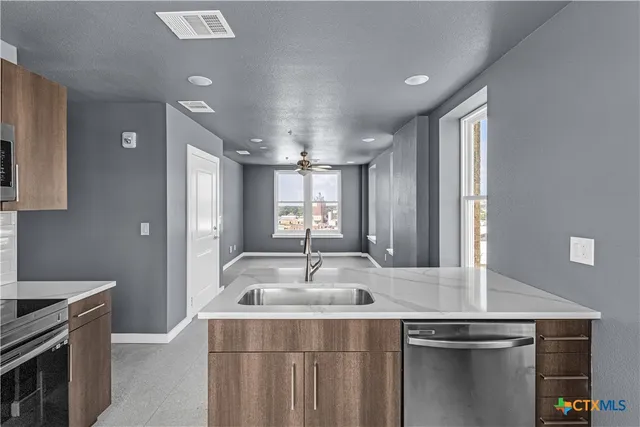 a kitchen with kitchen island a sink stainless steel appliances and window