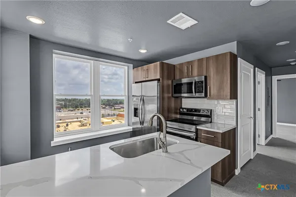 a kitchen with stainless steel appliances granite countertop a sink stove and refrigerator