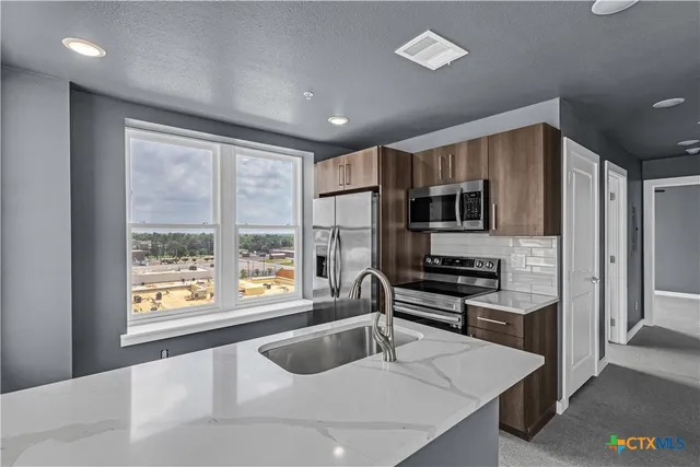 a kitchen with stainless steel appliances granite countertop a sink stove and refrigerator