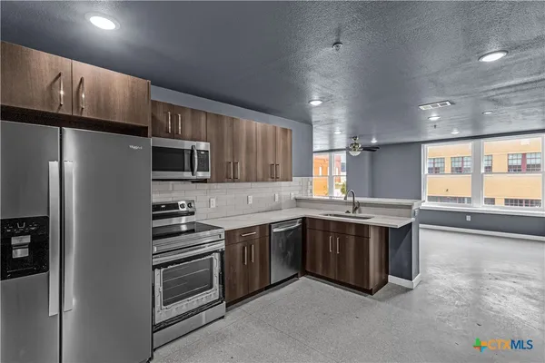 a kitchen with stainless steel appliances a sink stove and refrigerator