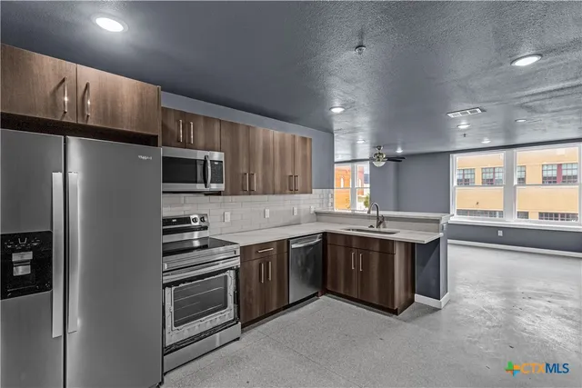 a kitchen with stainless steel appliances a sink stove and refrigerator