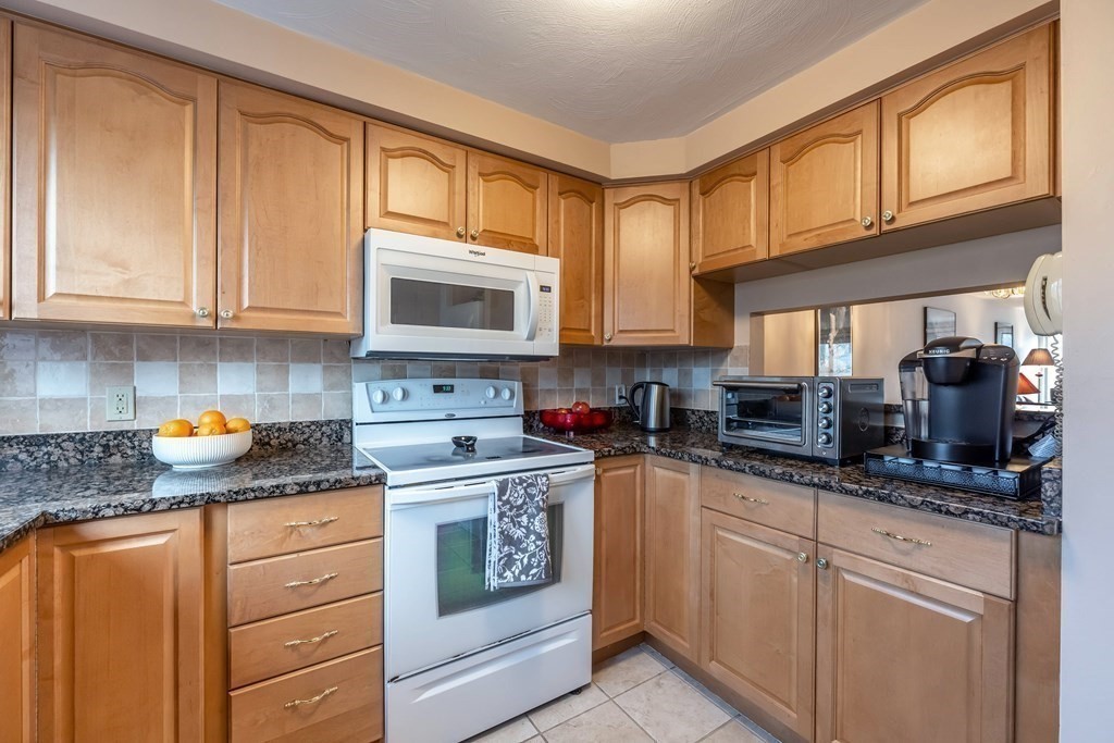 101 Mill Pond, Unit 101 North Andover, MA 01845 - Photo 5 of 27 a kitchen with granite countertop stainless steel appliances a stove a sink and a microwave