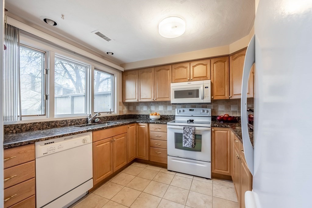 101 Mill Pond, Unit 101 North Andover, MA 01845 - Photo 6 of 27 a kitchen with stainless steel appliances granite countertop a stove sink and microwave