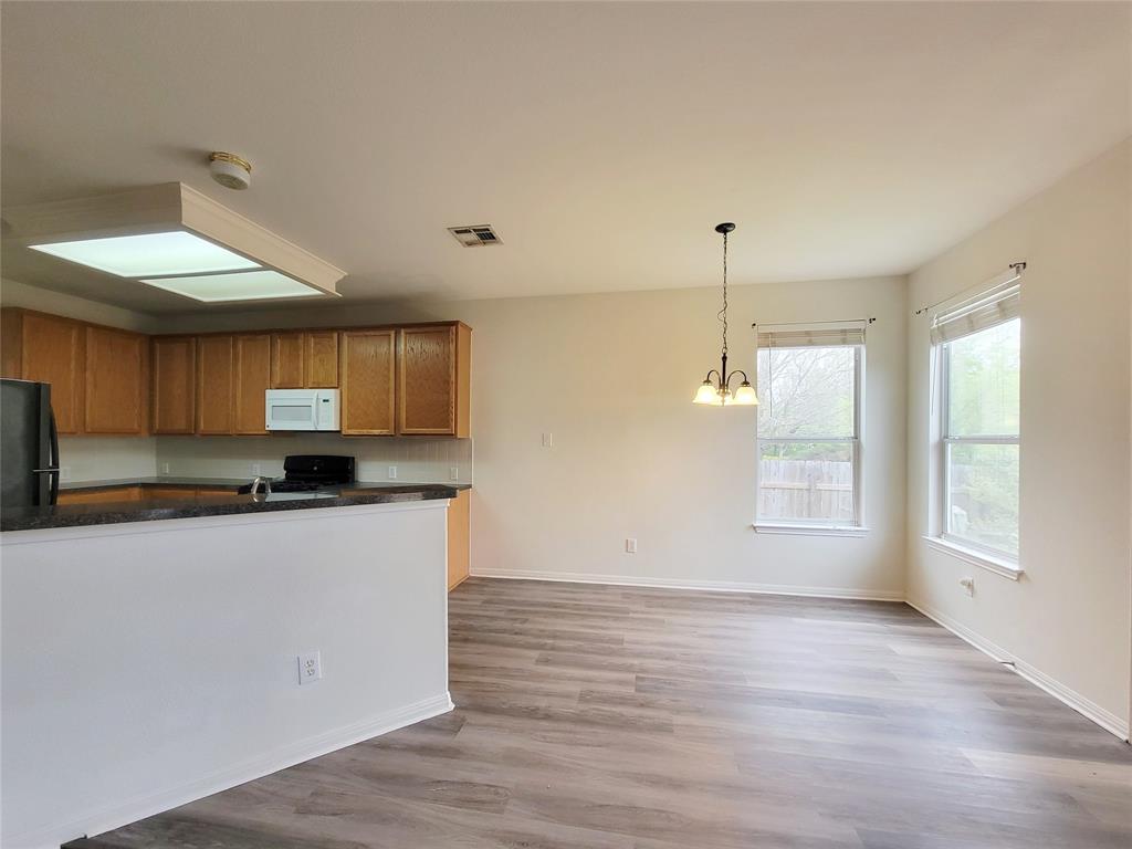6708 Kilt Court Austin, TX 78754 - Photo 13 of 32 a kitchen with stainless steel appliances granite countertop a stove a sink and white cabinets with wooden floor