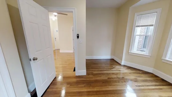 a view of a hallway with wooden floor and closet area