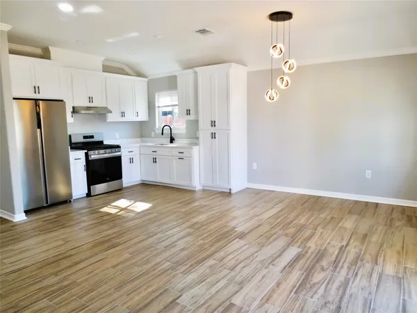 a large kitchen with cabinets wooden floor and stainless steel appliances