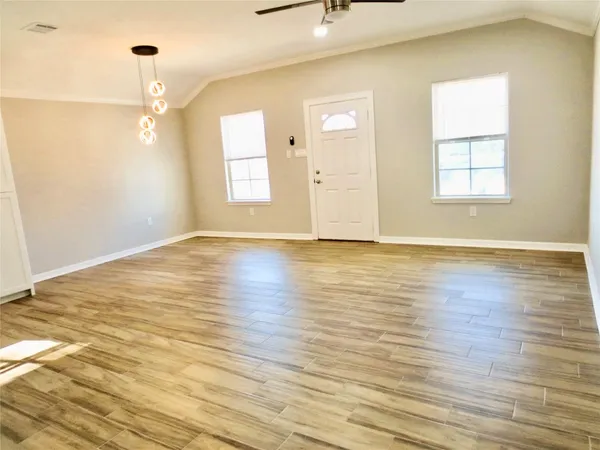 an empty room with wooden floor cabinet and windows
