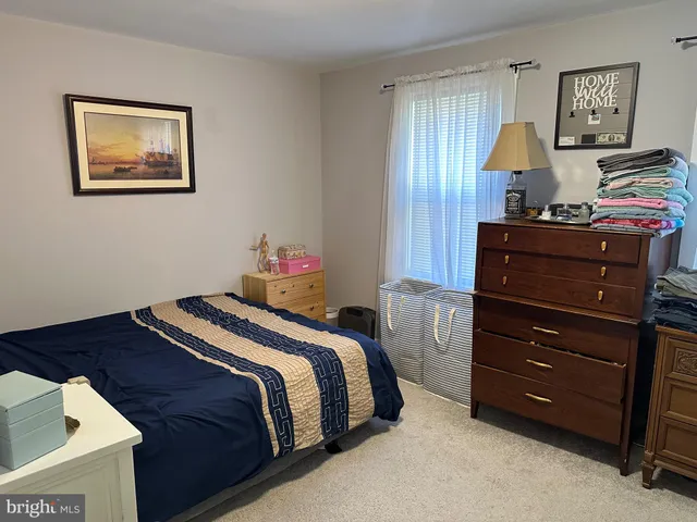 a bedroom with a bed and a lamp on dresser