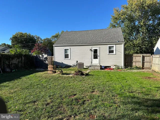 a backyard of a house with table and chairs plants and large tree