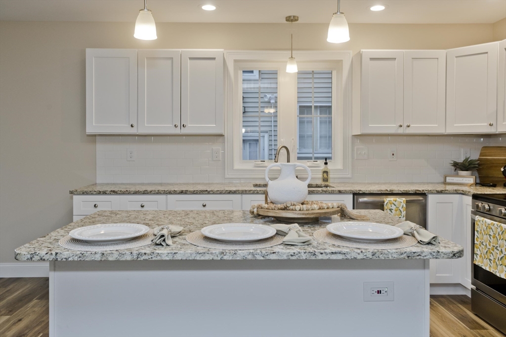 40 Preston Street Springfield, MA 01109 - Photo 7 of 32 a kitchen with stainless steel appliances granite countertop a sink a stove white cabinets and white countertops with wooden floor