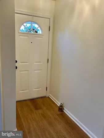 an empty room with a chandelier fan and wooden floor