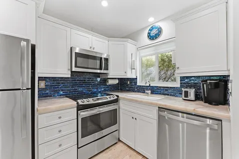 a kitchen with granite countertop white cabinets and stainless steel appliances