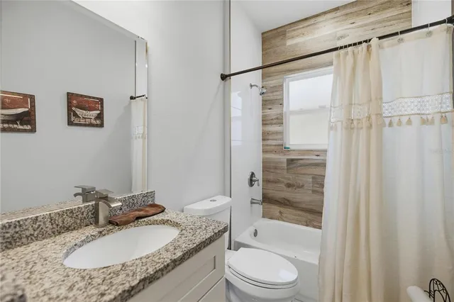 a bathroom with a granite countertop toilet sink and mirror
