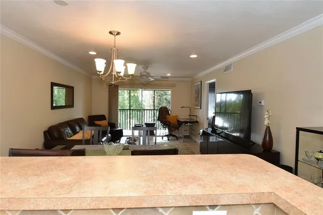a living room with furniture a chandelier a flat screen tv and a large window