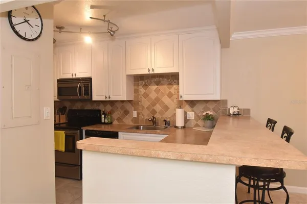 a kitchen with kitchen island granite countertop a sink a stove and a microwave oven with wooden floor