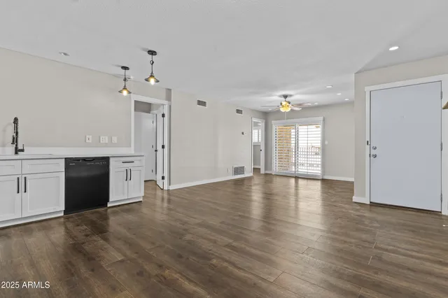 a view of an empty room with window and wooden floor