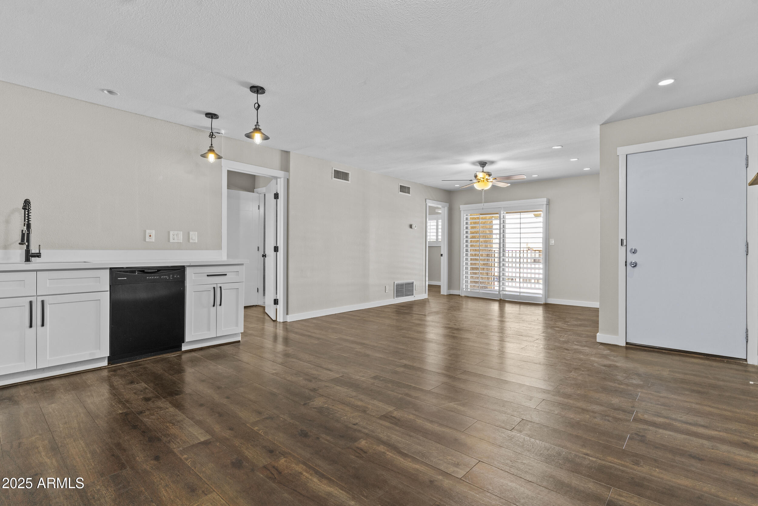 a view of an empty room with window and wooden floor