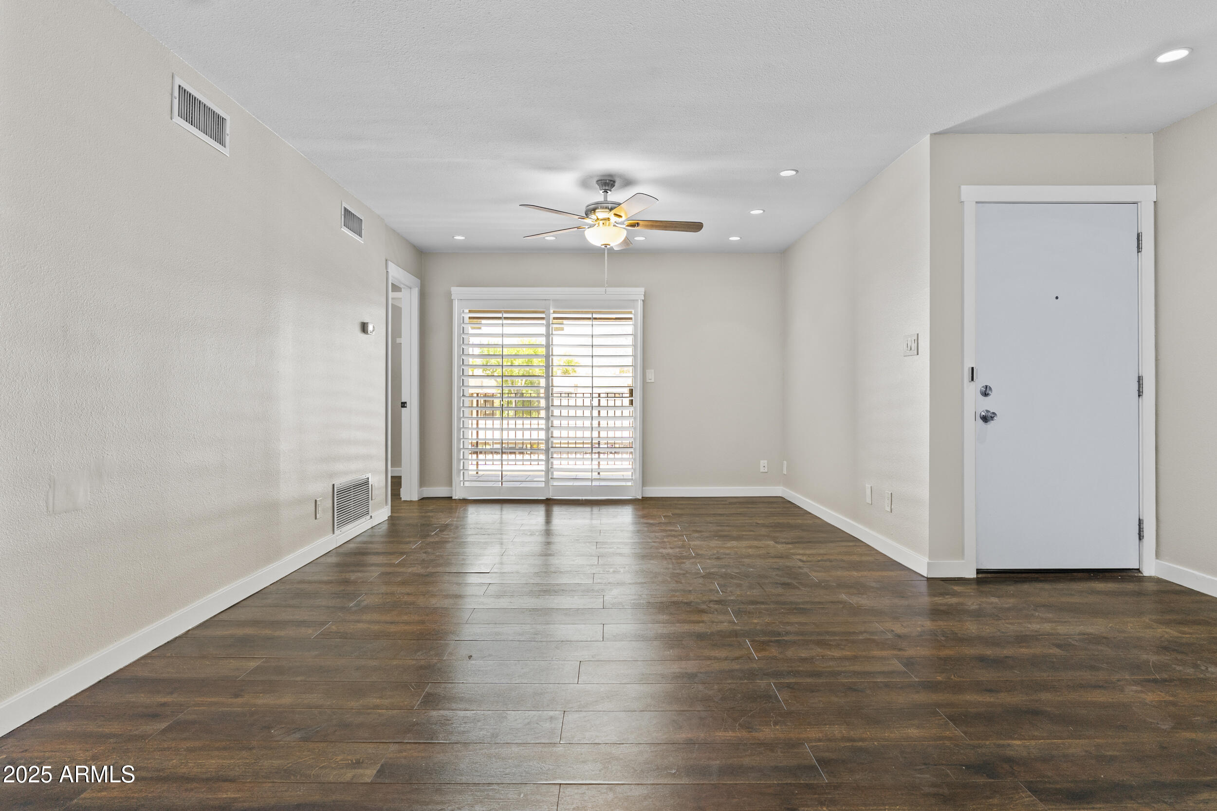 5525 East Thomas Road, Unit K16 Phoenix, AZ 85018 - Photo 11 of 36 an empty room with wooden floor chandelier fan and windows