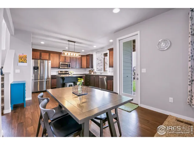 a kitchen with stainless steel appliances a dining table chairs and wooden floor