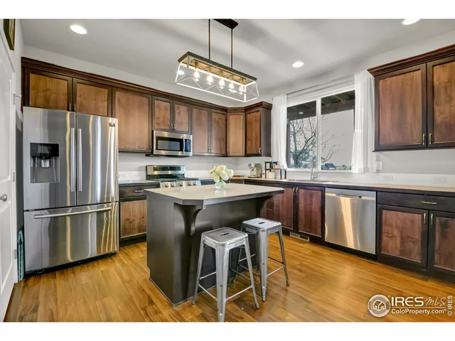 a kitchen with stainless steel appliances granite countertop a stove a sink dishwasher a refrigerator with a dining table and chairs
