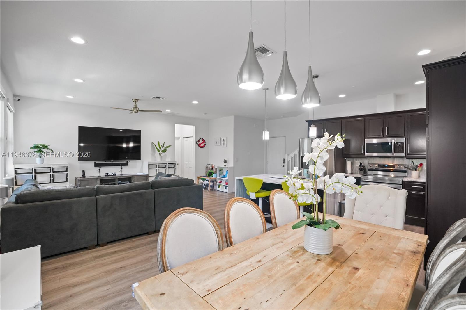 2913 Cascada Isle Way Cooper City, FL 33024 - Photo 6 of 50 a kitchen with stainless steel appliances kitchen island granite countertop a refrigerator a stove a sink dishwasher a dining table and chairs with wooden floor