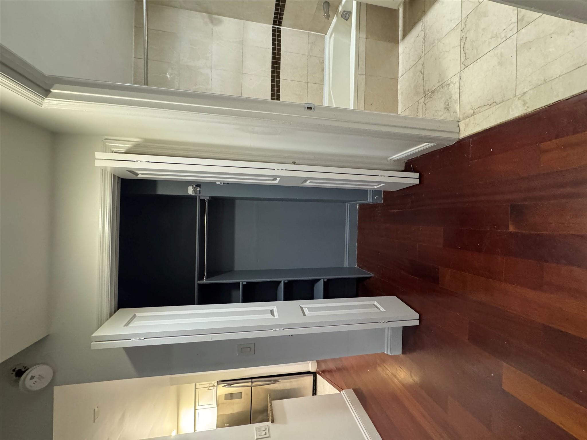 143-41 84th Drive, Unit 1A Queens, NY 11435 - Photo 6 of 7 a view of walk in closet with wooden floor and stairs