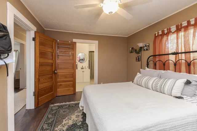 a bedroom with a bed a dresser and wooden floor
