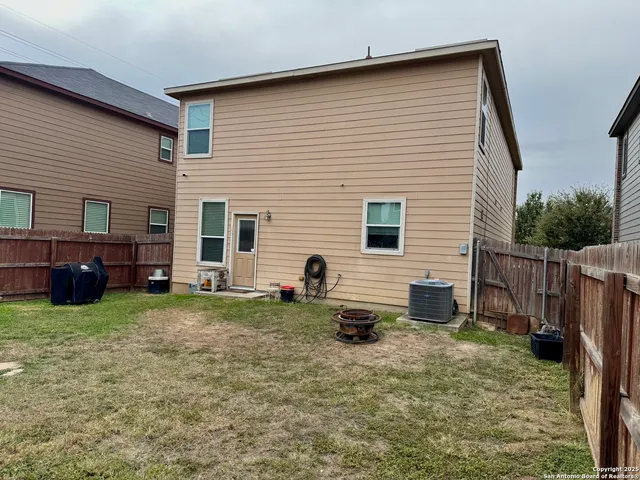 a view of a house with backyard and wooden fence