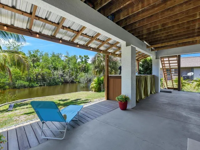 a view of a chairs and table in the patio next to a yard