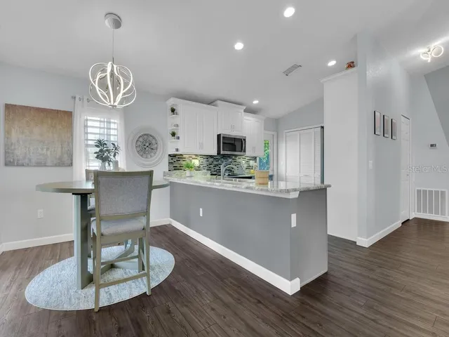 a living room with kitchen island granite countertop furniture and a chandelier