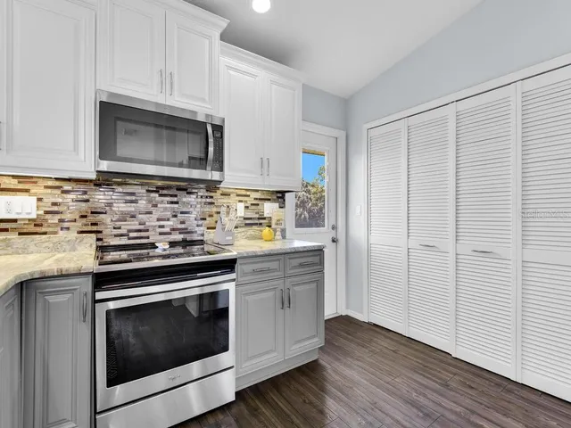 a kitchen with cabinets stainless steel appliances and wooden floor