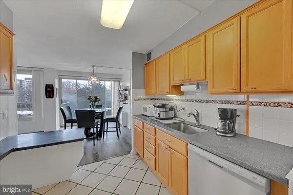 a kitchen with stainless steel appliances granite countertop a sink a stove a dining table and chairs with wooden floor