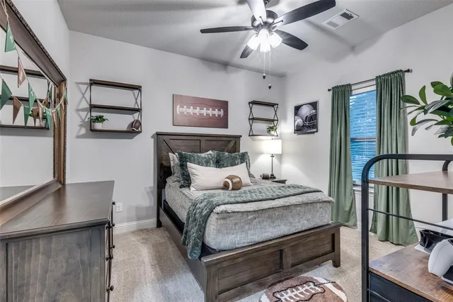 a bedroom with a bed a desk and painting on the wall