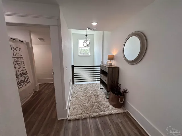 a hallway with stairs and wooden floor