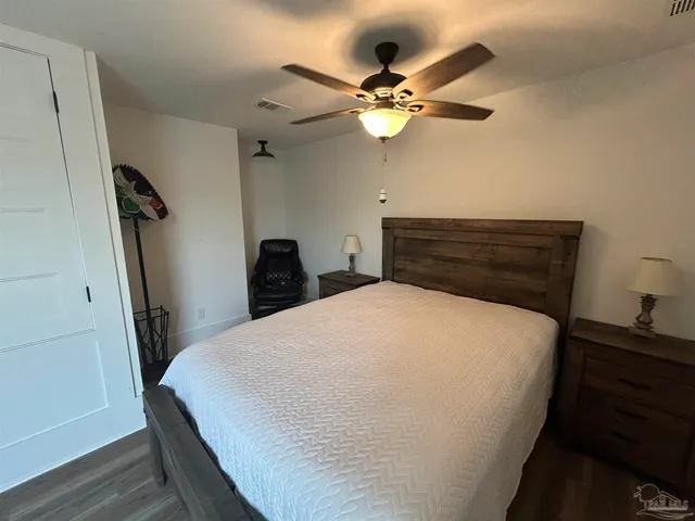 a view of a room with wooden floor ceiling fan and windows