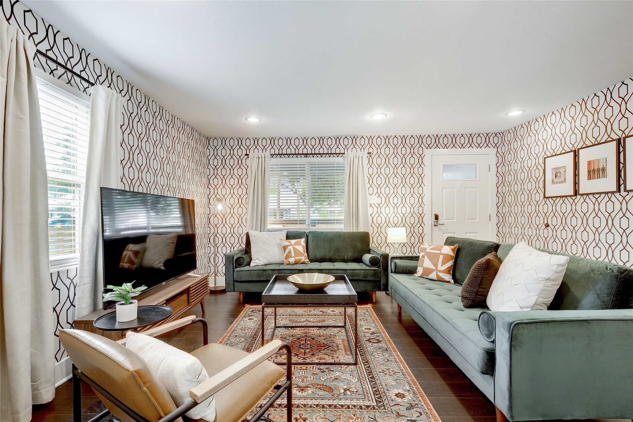 Living area with wallpapered walls, dark wood-style floors, and recessed lighting