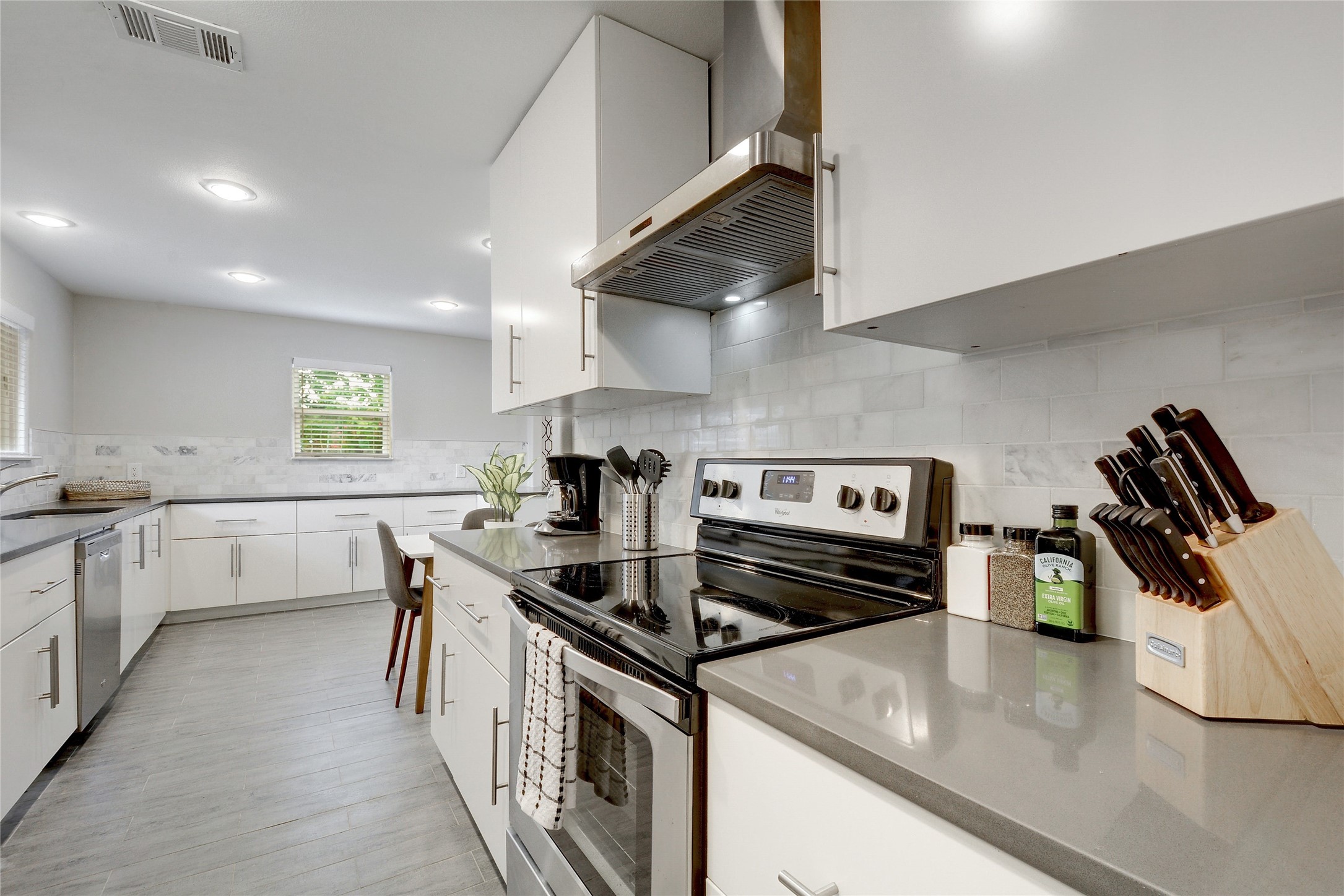 Undisclosed Address Austin, TX 78721 - Photo 11 of 35 Kitchen with stainless steel appliances, white cabinetry, dark stone counters, and light wood-style flooring