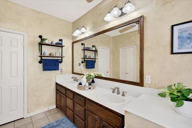 a bathroom with double vanity sinks a vanity a lamp and a mirror