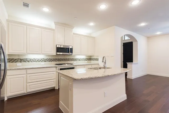 a kitchen with granite countertop white cabinets and stainless steel appliances