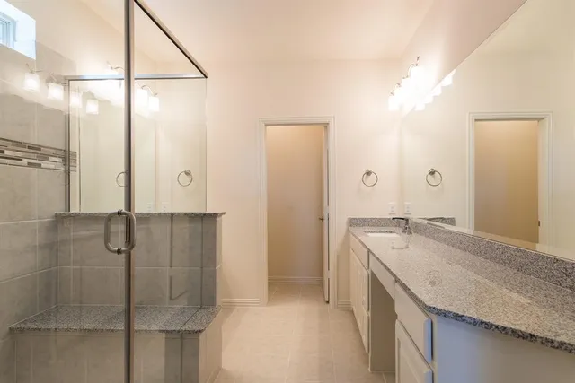 a bathroom with a granite countertop sink a mirror and shower