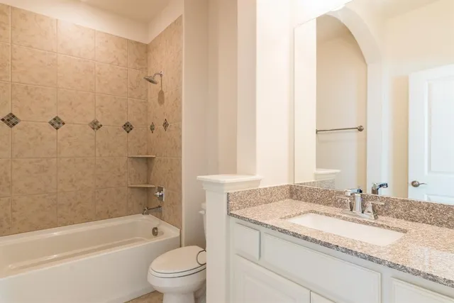 a bathroom with a granite countertop sink a toilet and bathtub