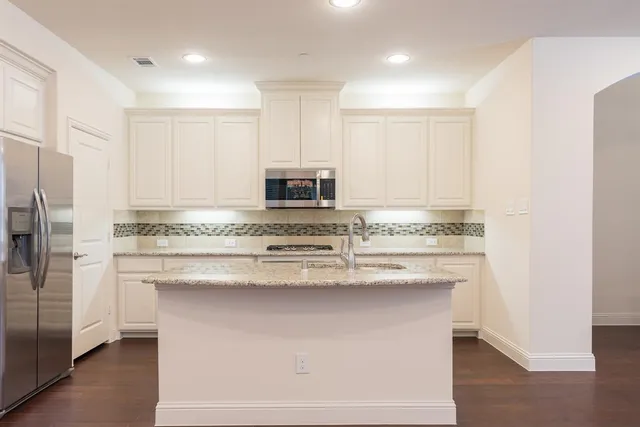 a kitchen with kitchen island granite countertop white cabinets and stainless steel appliances