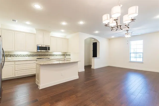 a kitchen with stainless steel appliances granite countertop a dishwasher a stove and white cabinets with wooden floor