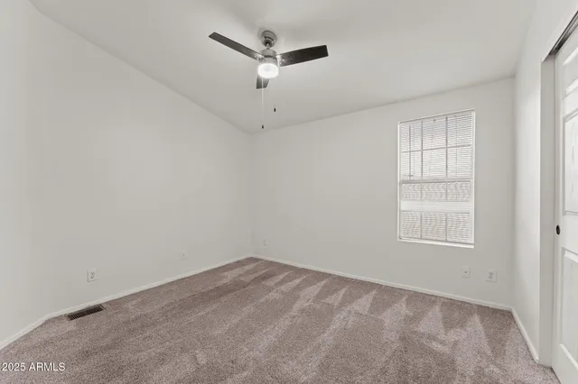 an empty room with a window and a ceiling fan