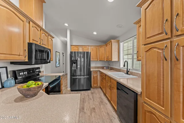 a kitchen with stainless steel appliances granite countertop a refrigerator a stove and a sink with wooden floor