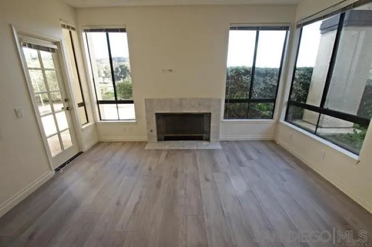 wooden floor fireplace and windows in an empty room